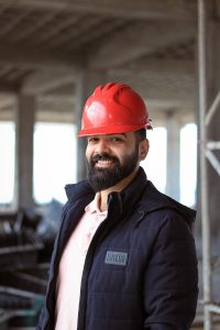 Construction worker wearing a red hard hat and jacket on a UK site